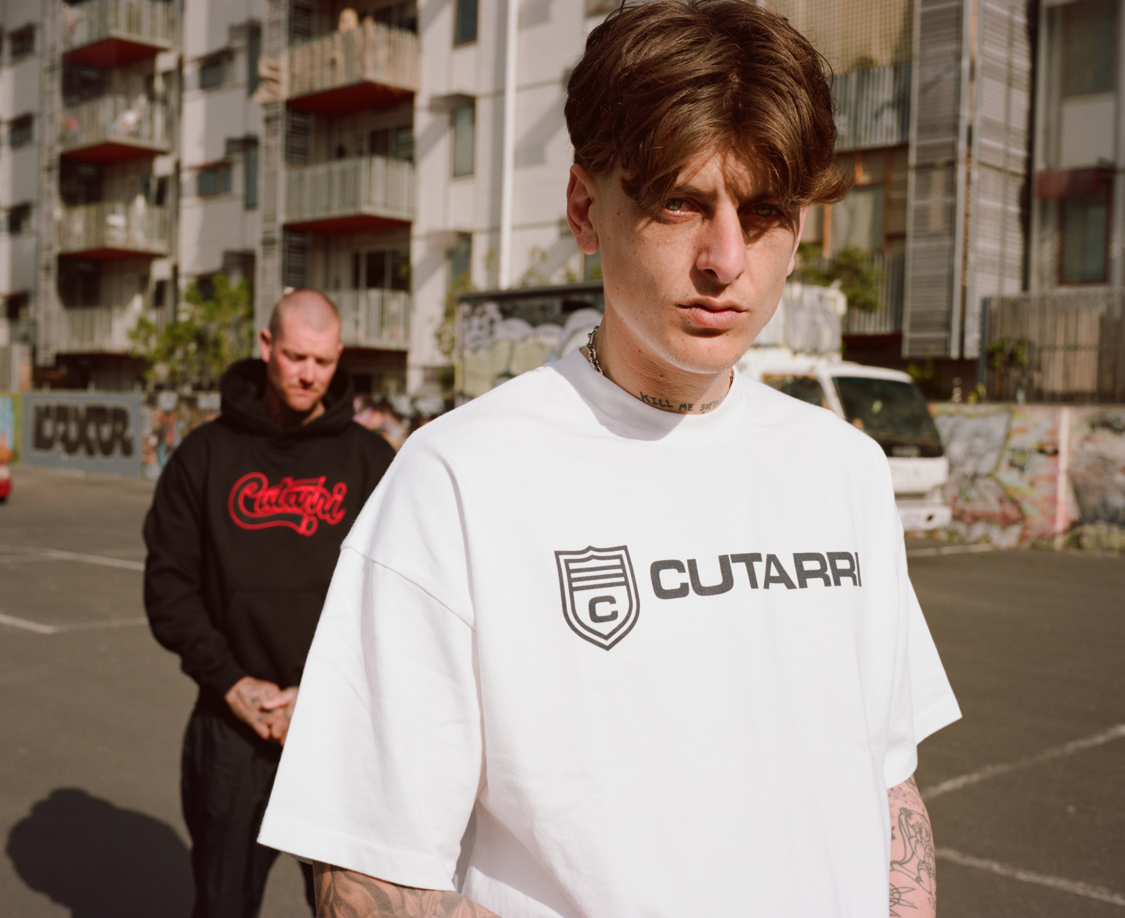 Person wearing a white t-shirt with Cutarri branding in an urban setting