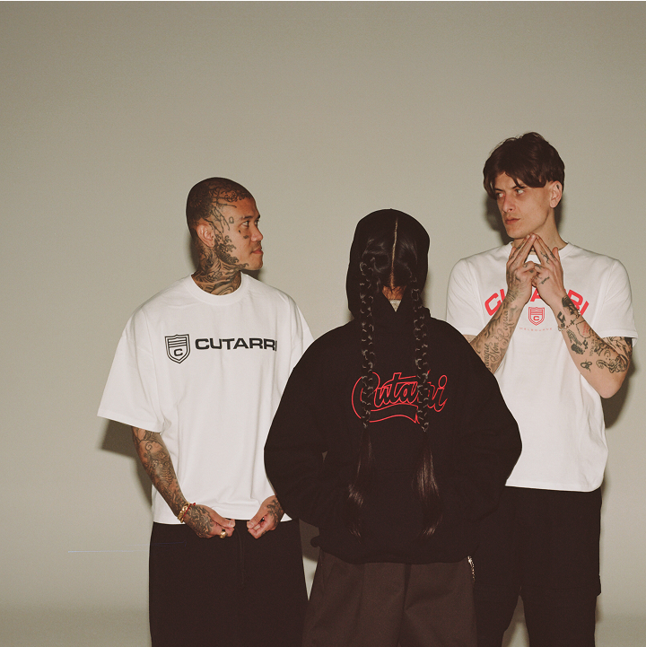 Three people wearing white and black clothing with 'CUTARRI' branding against a plain background.